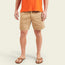 A person wearing an orange t-shirt, Westside Day Shorts in a soft cotton blend, and brown sandals stands against a plain light background. The image shows the outfit, including geometric embroidery on the shorts, from the shoulders down.