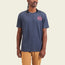 A person wearing a navy blue Howler blended t-shirt with a small pink graphic on the left chest and tan pants stands against a plain light background, enjoying maximum comfort from the soft cotton-poly blend.