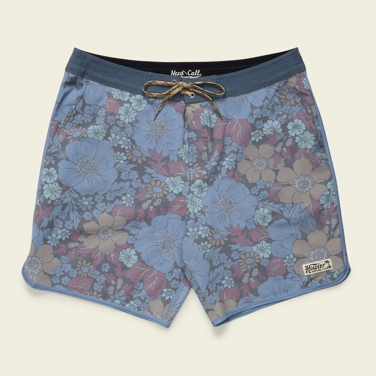 Blue floral-patterned Bruja Boardshorts for men, featuring stretchy fabric, a drawstring waist, draining front pockets, and a Howler Bros patch on the bottom left leg, laid flat on a light background.