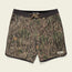 A pair of Bruja Boardshorts with a tree bark and leaves camouflage pattern, featuring stretchy fabric, a black waistband, brown drawstring, draining front pockets, and a small white Howler label near the bottom hem.