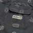 Close-up of a dark gray boardshorts pocket with abstract white patterns and a stitched Howler Brothers label under a palm tree graphic. The pocket, part of 7” inseam shorts, features two button holes at the bottom.