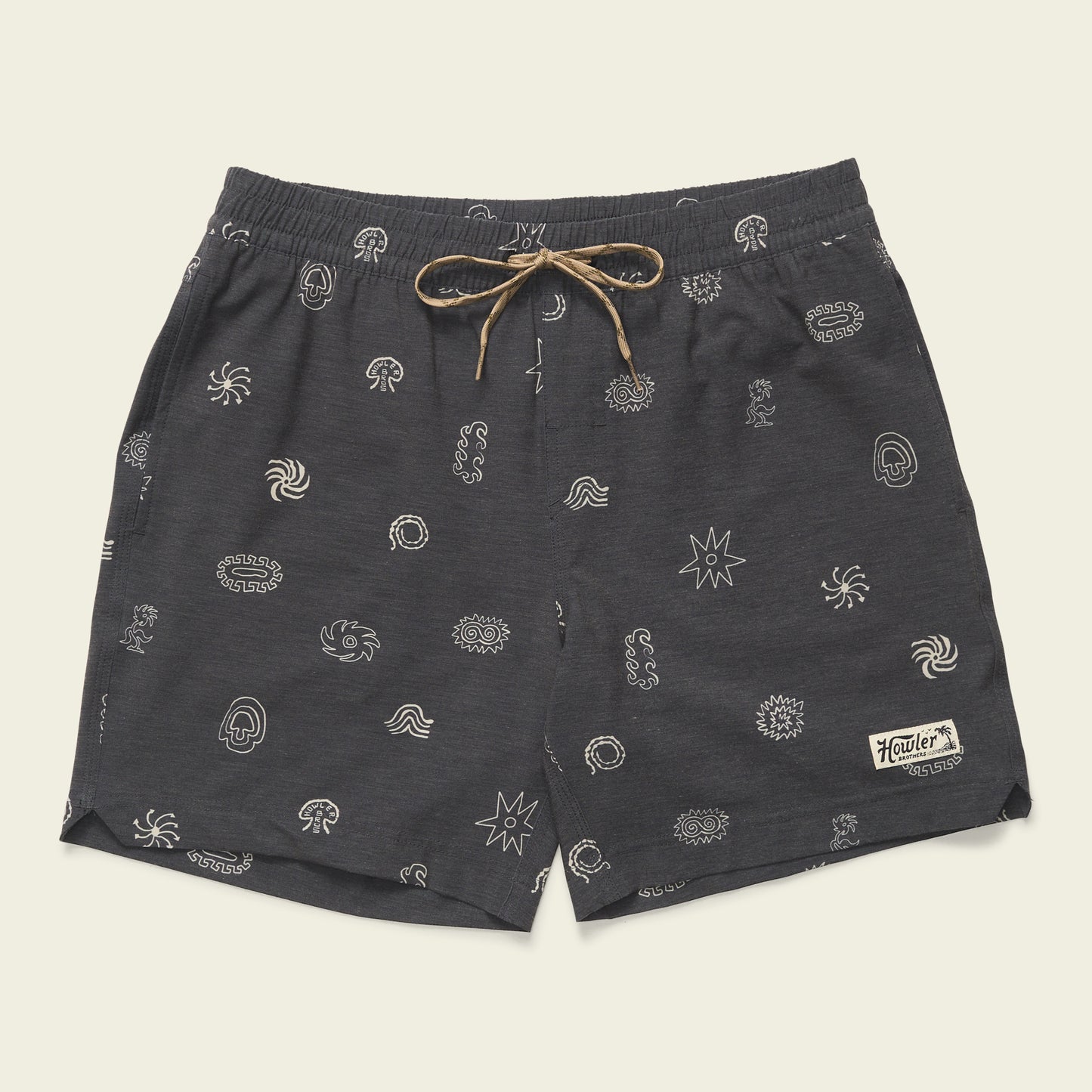 Dark gray boardshorts featuring a 7” inseam, tan drawstring, and small white abstract patterns throughout. An elastic waistband ensures comfort, while a rectangular patch with “Howler” is sewn near the lower left hem.