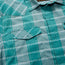 Close-up of a teal and light blue plaid lightweight stretch shirt with buttons and two chest pockets, one pocket flap partially open. The shirt has a pointed collar, visible stitching, and features a vented yoke for added comfort.