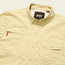 Light yellow plaid Matagorda Shirt with a collar, front pocket, and a small zipper near the left chest. This quick drying travel shirt features the Howler Bros brand label inside the collar.