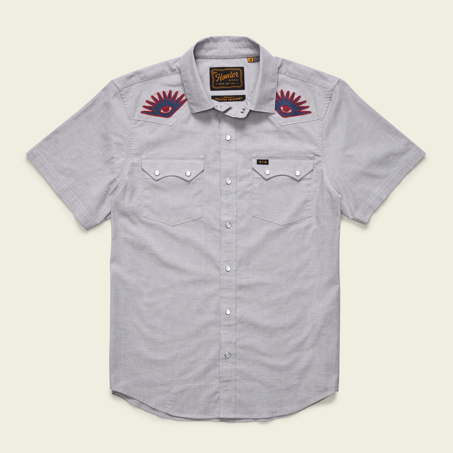 A light gray Crosscut Deluxe Shortsleeve summer shirt with two chest pockets and red motif embroidery of eye designs above each pocket on the upper chest area.