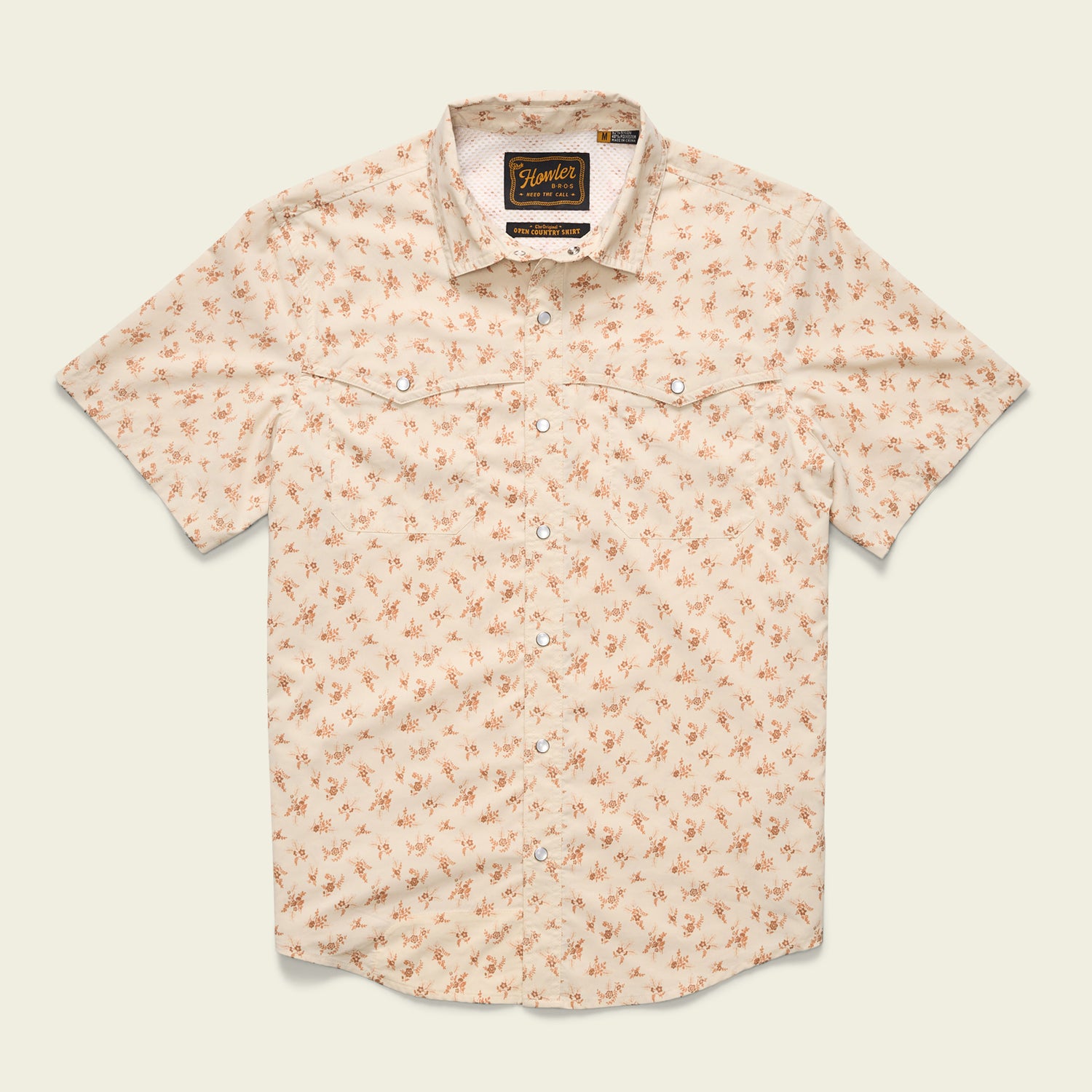 A short-sleeved, light beige button-up shirt with a small orange floral pattern, two chest pockets, pearl snaps, and a collar, crafted from nylon-poly fabric and laid flat against a plain background.