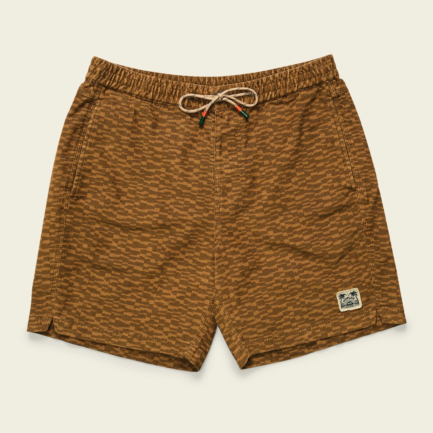 Brown patterned swim trunks with an elastic waistband, drawstring, and side pockets. Inspired by Pressure Drop Cord Shorts, these comfort shorts feature a palm tree patch on the lower left leg and are laid flat on a light background.
