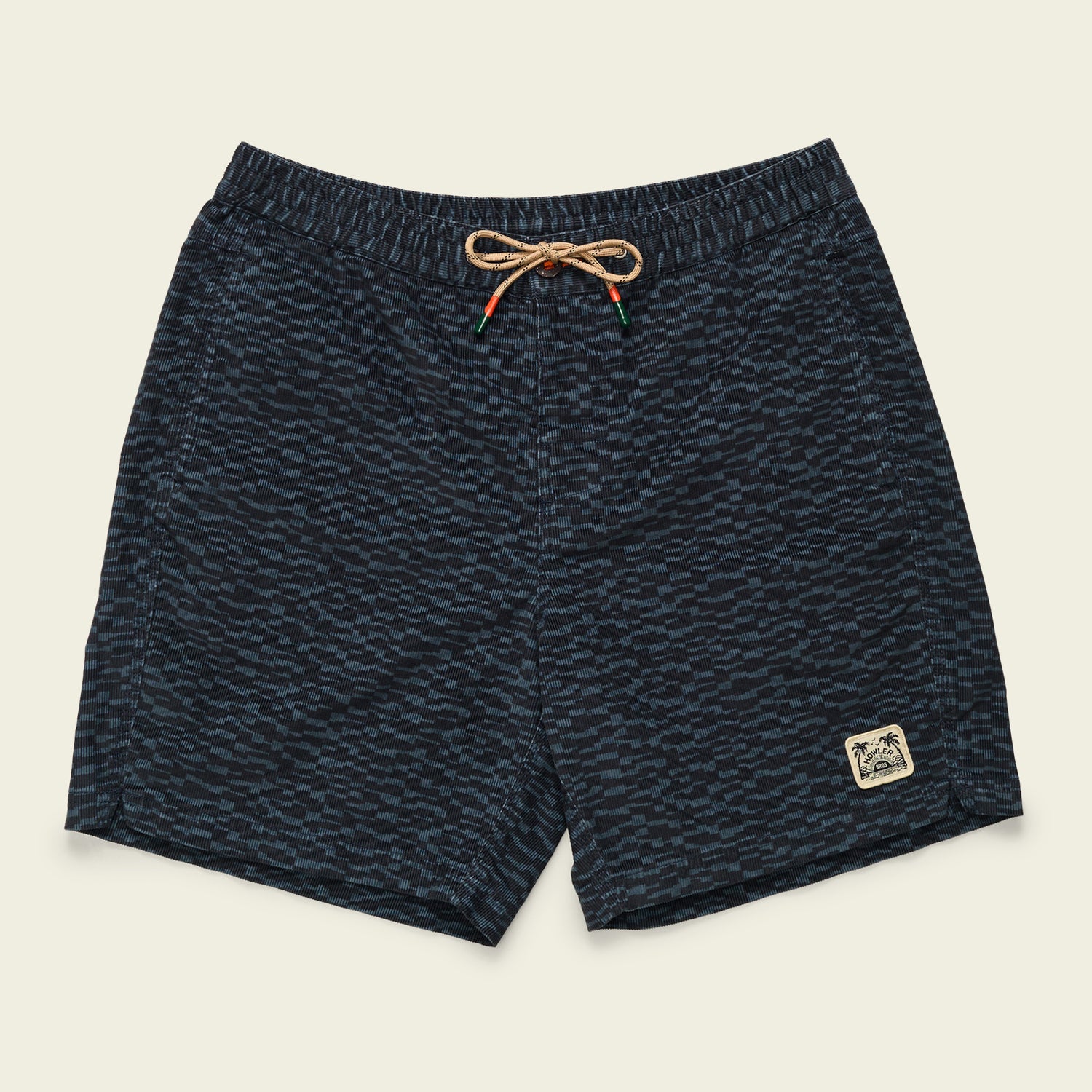 Navy blue swim trunks with a subtle wave pattern, an elastic waistband with a tan drawstring, and a small patch featuring palm trees and waves on the front left leg deliver all day comfort inspired by Pressure Drop Cord Shorts.