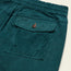 Close-up of a teal stretch cotton corduroy pocket with a flap, button closure, and elastic waistband—features seen on the Pressure Drop Cord Shorts—plus two small eyelets at the bottom for these comfortable shorts.