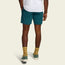 A person stands facing away, wearing a white T-shirt and comfortable shorts—teal Pressure Drop Cord Shorts made from stretch cotton corduroy—paired with yellow patterned socks and green sneakers against a plain light background.