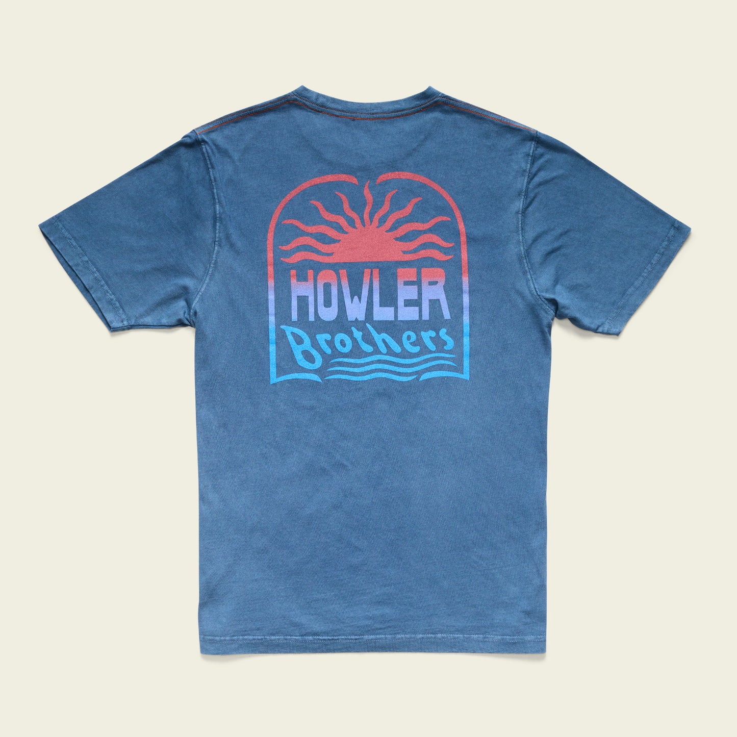 A blue cotton t-shirt featuring a graphic on the back of a setting sun with red and orange rays, above the text Howler Brothers in stylized font with wavy lines underneath, finished with a resin-washed vintage look.
