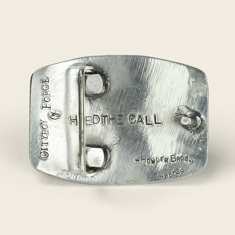 A sterling silver buckle engraved with CITYBOY FORGE, HEED THE CALL, and -HOWLER BROS. HB6029. The back features a belt loop and clasp—an iconic piece from Cityboy Forge x Howler Brothers.
