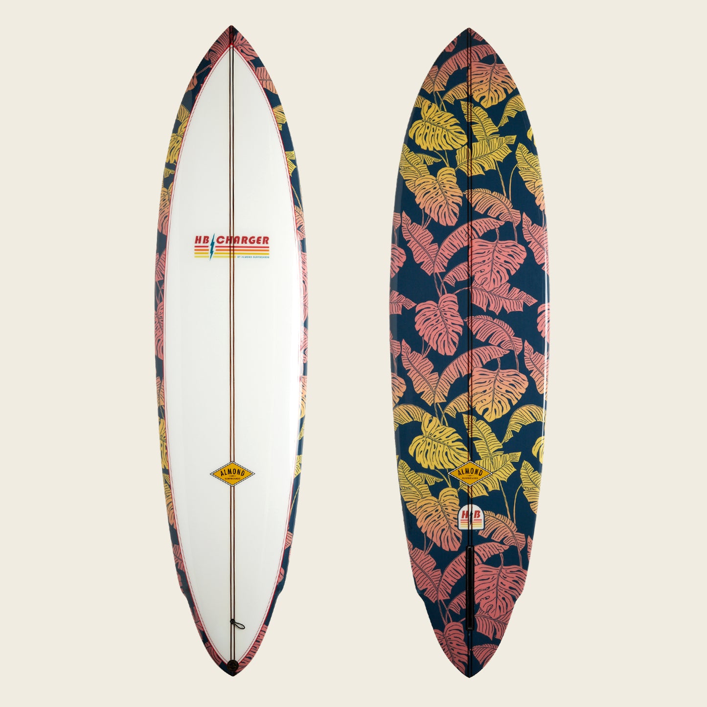 Two surfboards side by side: the left is mostly white with patterned edges and an HB Charger surfboard logo, while the right showcases a bold tropical leaf print in pink and yellow on a dark background.