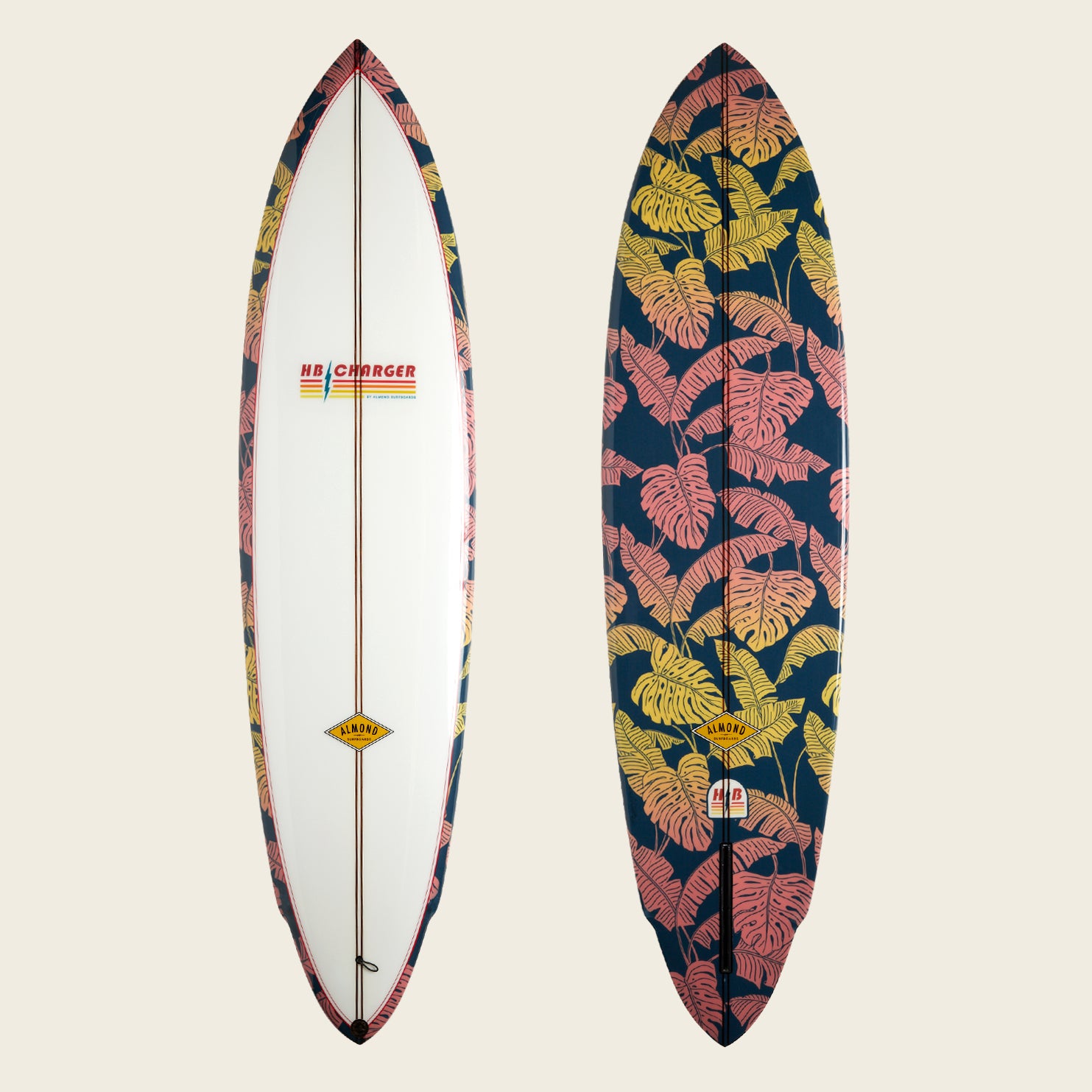 Two surfboards side by side: the left is mostly white with patterned edges and an HB Charger surfboard logo, while the right showcases a bold tropical leaf print in pink and yellow on a dark background.