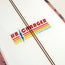 Close-up of an HB Charger surfboard from Almond Surfboards, featuring retro red, yellow, and orange stripes with a blue lightning bolt on white. Two brown lines run alongside the logo from the Howler Shaper Series.