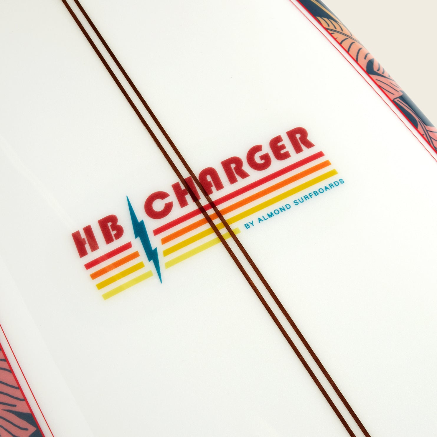 Close-up of an HB Charger surfboard from Almond Surfboards, featuring retro red, yellow, and orange stripes with a blue lightning bolt on white. Two brown lines run alongside the logo from the Howler Shaper Series.