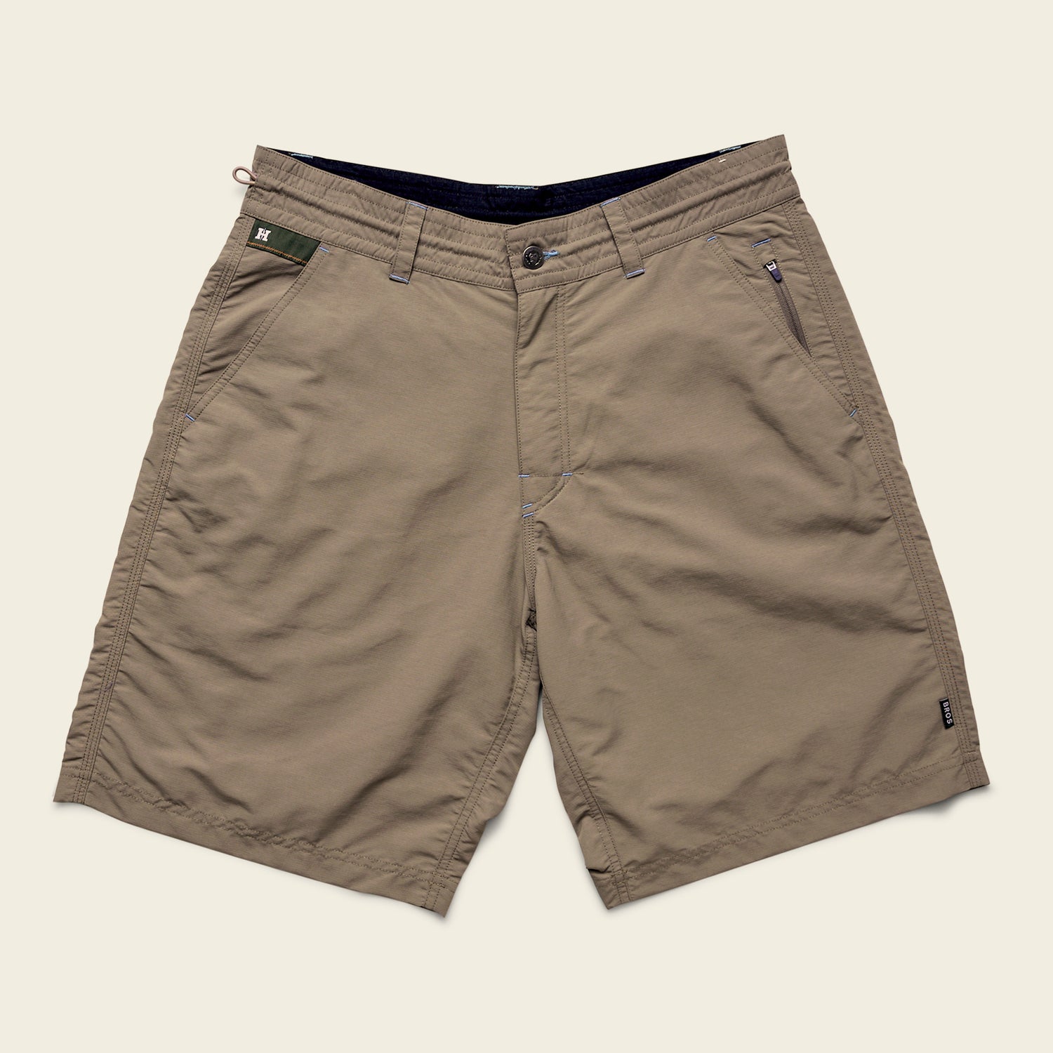 Khaki-colored Horizon Hybrid Shorts with front button and zipper closure, two side pockets, and one zippered pocket on the right. Made from durable ripstop fabric, these versatile shorts are laid flat on a light beige background.