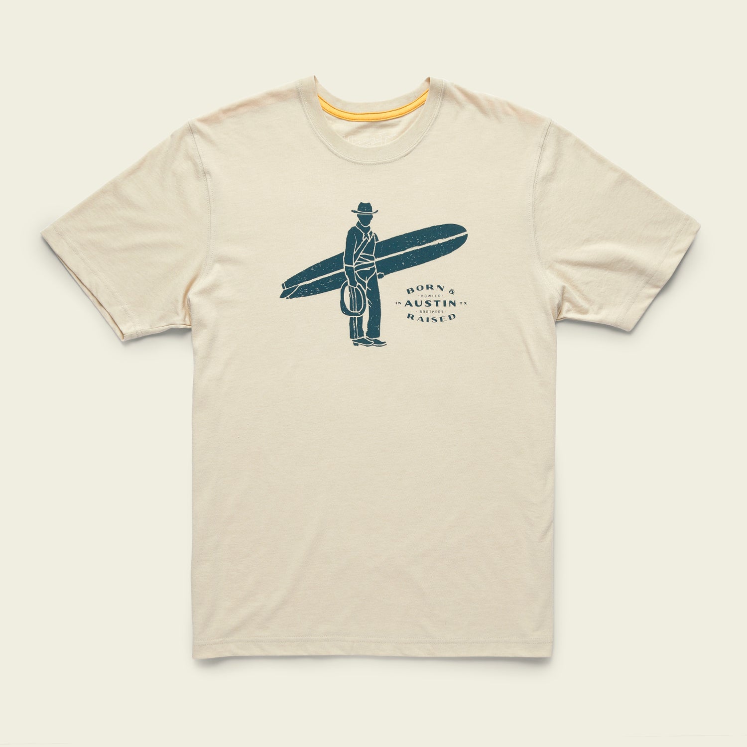 A beige T-shirt from the Howler Select T-Shirts collection featuring classic Howler designs: a person in a suit and hat holding a surfboard, with Born & Austin Raised beside the figure, crafted from a soft cotton-poly blend.