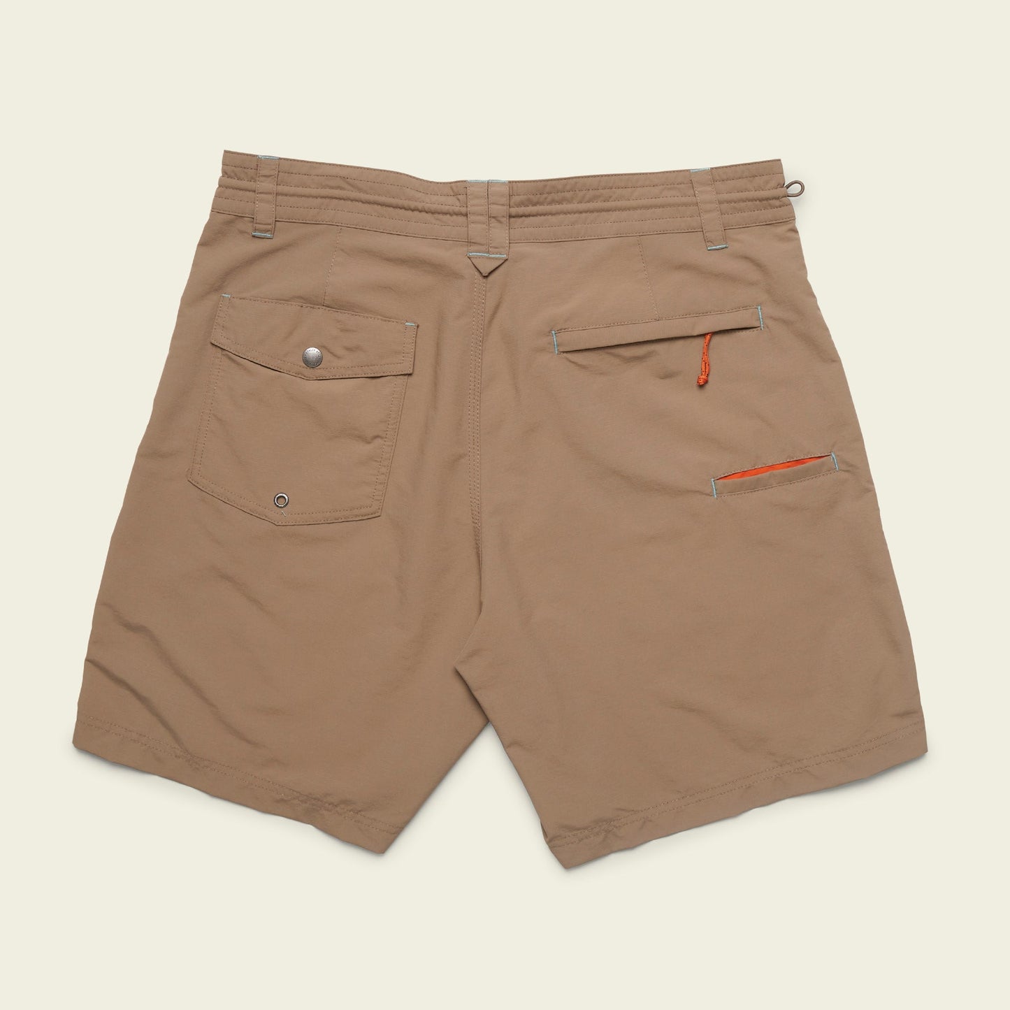 Tan Horizon Hybrid Shorts viewed from the back, featuring a flap pocket with snap closure on the left, a zippered pocket with an orange pull on the right, and belt loops along the waistband. Made from durable ripstop fabric for versatile wear.