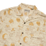 Beige button-up shirt in soft slub fabric with a mystical-themed print inspired by vintage Hawaiian shirts—skulls, crescent moons, snakes, and more in light brown and gold. Features a camp collar and visible Howler brand label inside the collar.