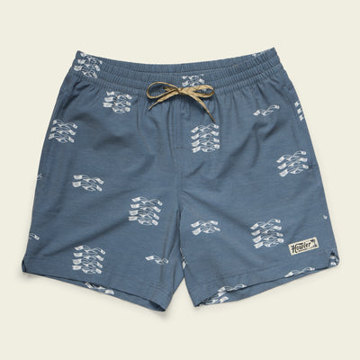 Blue boardshorts with a white abstract pattern, an elastic waistband with a beige drawstring, and a small Howler patch on the lower left leg, displayed flat on a light background.