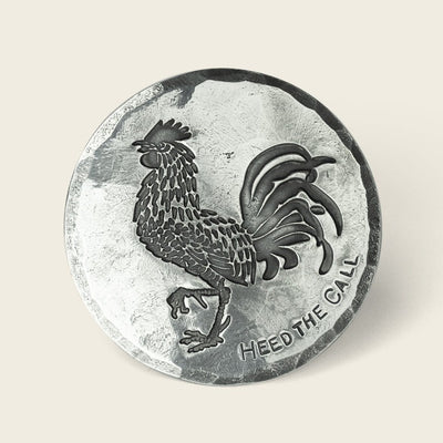 A round silver-colored coin from Cityboy Forge featuring an embossed rooster and the words HEED THE CALL engraved beneath it.
